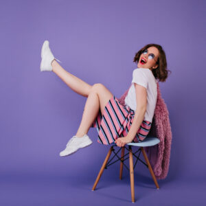 romantic-girl-white-shoes-sitting-chair-laughing-indoor-shot-carefree-curly-woman-posing-purple-wall-with-sincere-smile